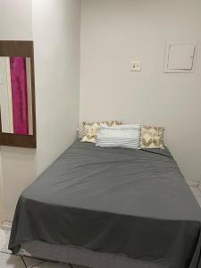 uma cama num quarto branco com um cobertor cinzento em Casa Maria Toda Linda N 53 em Belém