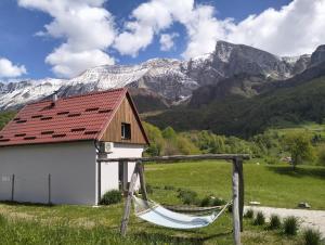 a hammock in front of a house and mountains at Holiday Home Krn&Relax in Kobarid