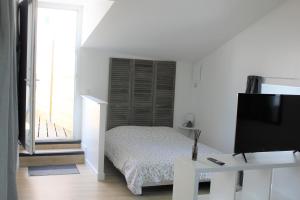 Habitación blanca con cama y TV en Le Petit Cosy - terrasse privée, en Lagord