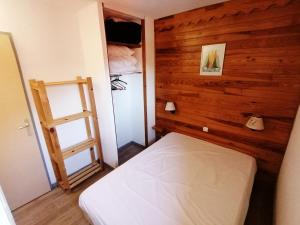 a bedroom with a white bed and a wooden wall at Appartement Saint-François-Longchamp, 3 pièces, 6 personnes - FR-1-635-61 in Saint-François-Longchamp
