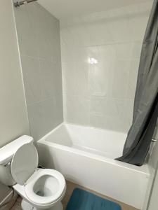 y baño con aseo y bañera con cortina de ducha. en Open modern concept 2BR basement, en Calgary