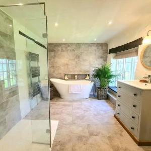 ein großes Badezimmer mit Badewanne und Dusche in der Unterkunft Stunning house, fenced garden, and outdoor dining! in Hennock