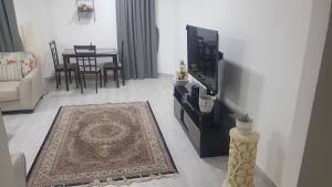 a living room with a tv and a couch and a rug at M apartment in Kuwait
