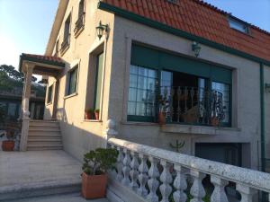 a house with a staircase and a balcony at Chalet con vistas al mar en la playa de A Lanzada in O Grove +3 photos