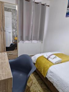 a bedroom with a bed and a blue chair at Lovely 2-Bed House in the heart of Woodhouse Leeds in Leeds