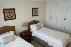 a bedroom with two beds and a table with a lamp at Pinnacle Point Golf Estate Lodge 78 in Mossel Bay +16 photos