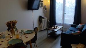 een woonkamer met een tafel en een tv bij Pause Bayeux in Bayeux