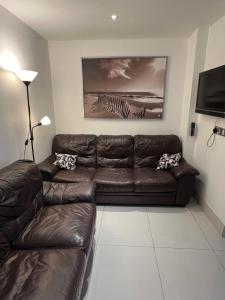 ein Wohnzimmer mit einem braunen Ledersofa und einem TV in der Unterkunft Lovely Home in Kimmage, Dublin in Dublin