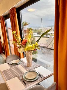 a vase of flowers on a table with a window at PENTHOUSE EXCLUSIVE VIEW , Iasi in Iaşi