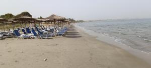 una fila de sillas y sombrillas en una playa en AIR-IN Rooms with magnificent views, en Artemida