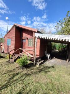 La cabaña في كونسيبسيون ديل أوروغواي: منزل احمر صغير مع مقعد وشرفه
