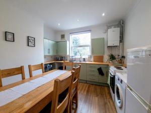 a kitchen with a wooden table and a refrigerator at Peaceful 4 bed townhouse in Brighton & Hove
