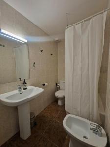 a white bathroom with a sink and a toilet at Hostal Rugaca in Huesca