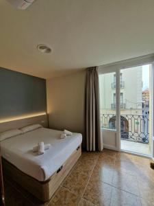 a bedroom with a bed and a large window at Hostal Rugaca in Huesca