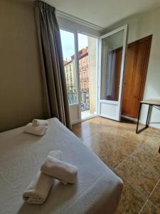 1 dormitorio con 2 toallas en una cama con ventana en Hostal Rugaca en Huesca