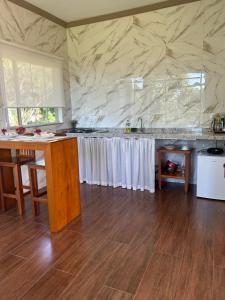 a kitchen with a counter with white curtains at Chales Maria Flor in Gonçalves