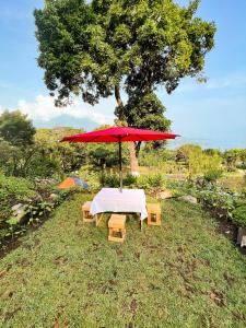 a picnic table with a red umbrella and benches at Paraíso en Atitlán in Panaranjo