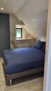 ein Schlafzimmer mit einem blauen Bett im Dachgeschoss in der Unterkunft Ancien moulin près d'un ruisseau in Sallen