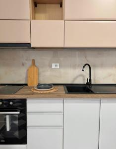 a kitchen with white cabinets and a sink at Gibel Apartments in Golem