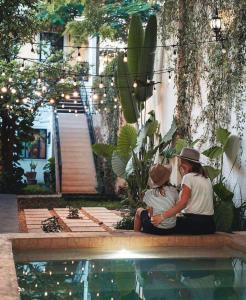 two women sitting on a bench next to a pool at Hotel & Hostal Boutique Casa Garza in Mérida