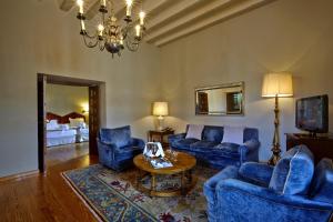 una sala de estar con muebles azules y una lámpara de araña. en Parador de Zamora en Zamora