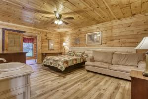 Dormitorio en cabaña de madera con cama y sofá en Suite Spot #242 en Pigeon Forge