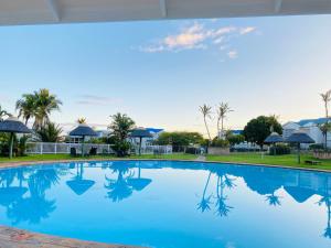 a large blue swimming pool with palm trees in the background at Pinnacle Point Golf Estate Lodge 78 in Mossel Bay