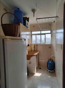 a small kitchen with a refrigerator and a sink at Apartamento pé na areia de frente para o mar in Mongaguá