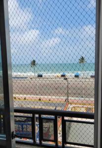 a view of a beach through a fence at Apartamento pé na areia de frente para o mar in Mongaguá