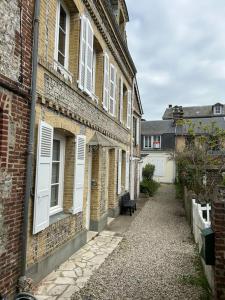 une allée entre deux bâtiments en briques avec un banc devant dans l'établissement Villa Roc Vaudieu - Charmante maison de pêcheurs, à Étretat