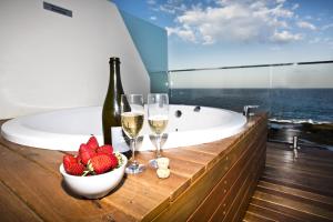 un bagno con vasca e una ciotola di fragole e bicchieri da vino di Ocean Front Motel a The Entrance