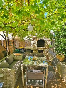 a patio with a couch and a table under a tree at Holiday Place Veli Dvor - vacation house with private garden in old town Punat in Punat