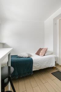 a white bedroom with a bed and a desk at Apartment for one - grey in Tallinn