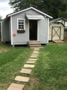 ein kleines weißes Haus mit einer Tür und einem Rasenplatz in der Unterkunft Petite Cajun Cottage Tiny House in Lafayette