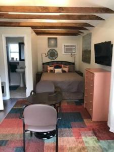 Schlafzimmer mit einem Bett, einem Tisch und einem TV in der Unterkunft Petite Cajun Cottage Tiny House in Lafayette