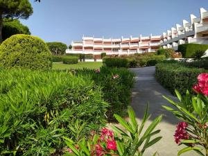 a large white building with bushes and flowers at Le Grau-du-Roi Studio 4 pers 150 M de la mer parking in Le Grau-du-Roi