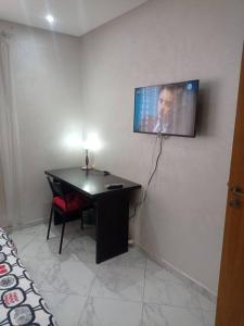 Zimmer mit einem Schreibtisch und einem TV an der Wand in der Unterkunft Appartement proche de toutes les commodités, RESIDENCE MARWA in Oulad Yakoub