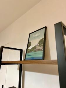 a framed picture on top of a wooden shelf at Confortable et Chic Appartement in Courbevoie