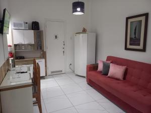 a living room with a red couch and a kitchen at 1 Quarto Turismo Teresópolis in Teresópolis