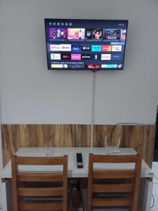 a desk with two chairs and a television on a wall at 1 Quarto Turismo Teresópolis in Teresópolis