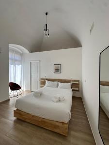 a white bedroom with a large bed and a chair at Casa Garruba 99 in Bari
