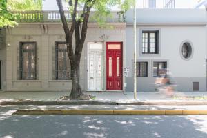 czerwone drzwi na budynku z drzewem przed w obiekcie Fliphaus New Ravignani 1600 - 3 Bd Pool Palermo w BuenosAires