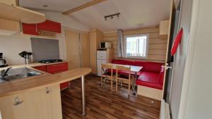 una pequeña cocina con mesa y sofá rojo en EGELE MOBIL-HOME prox Europapark et Rulantica en Boofzheim