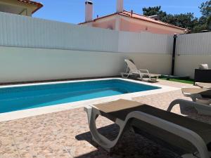a swimming pool with a table and chairs next to a house at Villa Luxsomar in Charneca