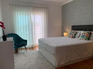 - une chambre avec un grand lit et une chaise verte dans l'établissement Villa Luxsomar, à Charneca