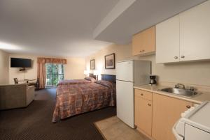 a bedroom with a bed and a kitchen with a sink at Canadian Inn in Surrey