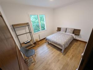 um quarto com uma cama, uma cadeira e uma janela em Maison rénovée sur Laruns em Laruns