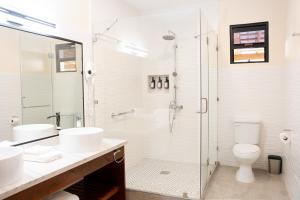baño con 2 lavabos y ducha de cristal en The West House Boutique Hotel en San Ignacio