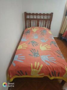 a bed with a orange comforter with hands on it at MINIMO 3 NOCHES HABITACION APARTAMENTO COMPARTIDO 3 PERSONAS - Aire acondicionado in Valledupar