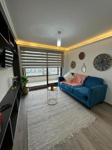 Moderno Depto. De 2 Dormitorios في لوس أنجلوس: غرفة معيشة بها أريكة زرقاء وساعة